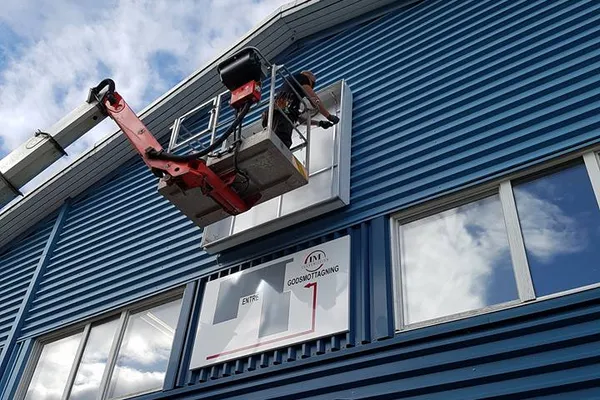 Pågående montering av stor fasadskylt åt IM Transmission AB